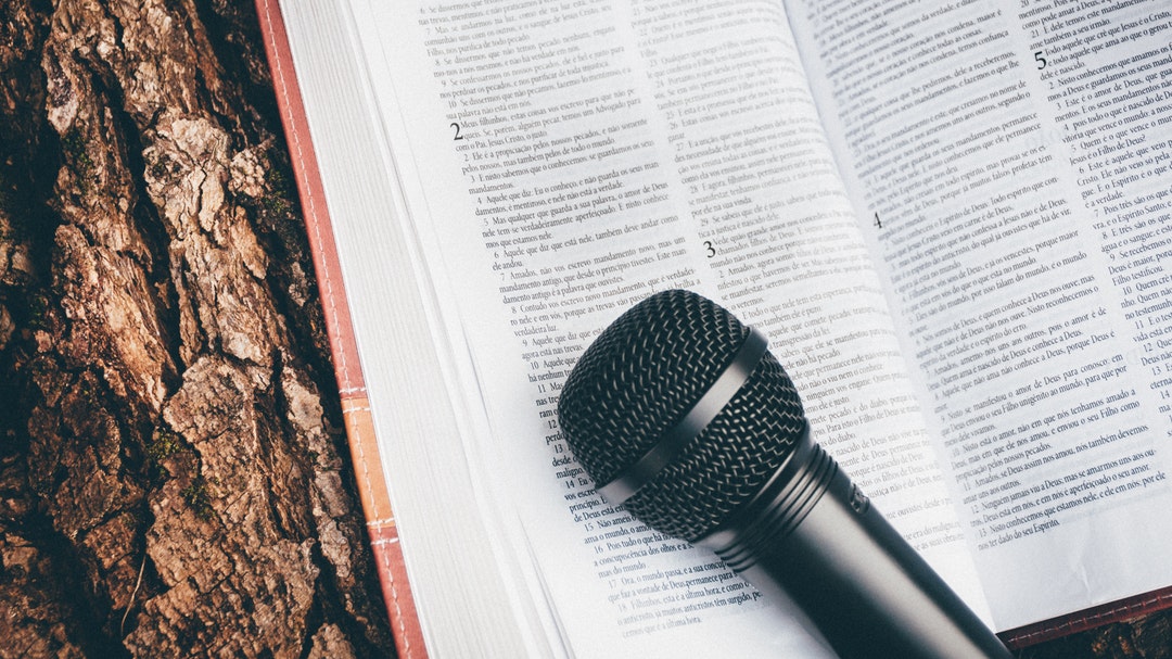 A microphone and bible resting on a tree stump
